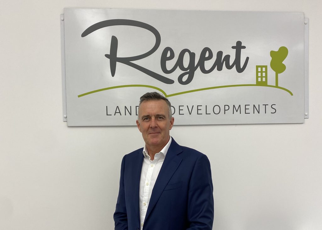 Tony Broome standing in front of Regent Land & Developments sign